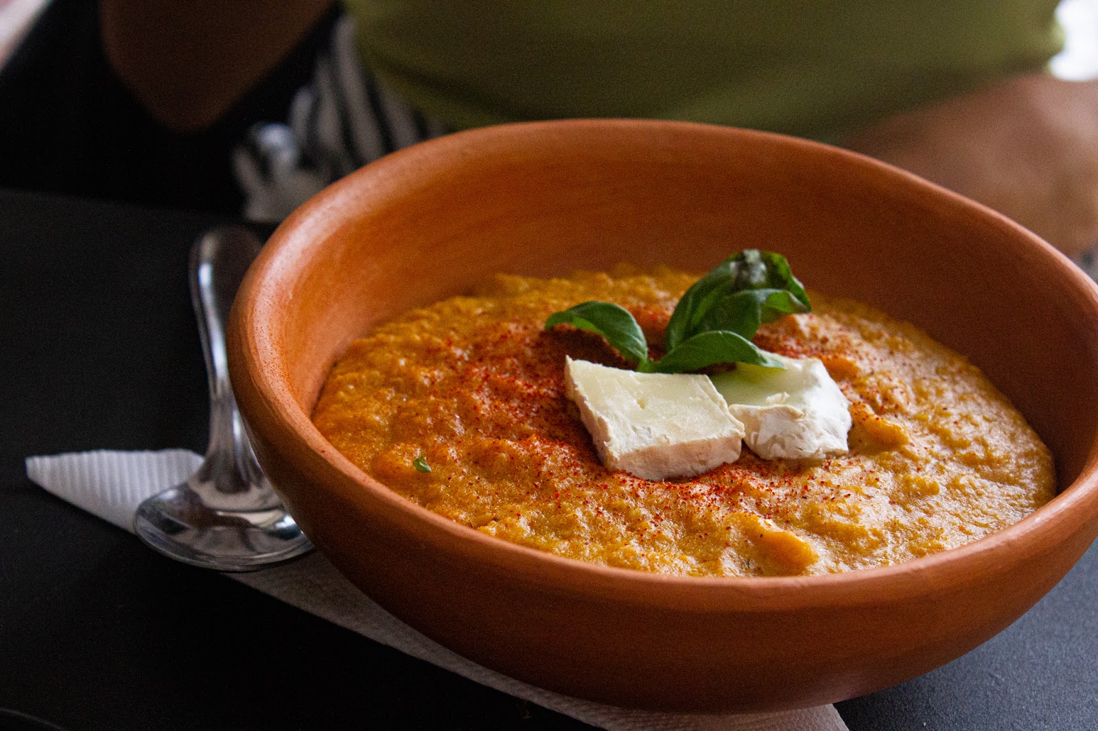 Hummus de habas servido en cuenco de barro, con páprika y queso fresco.